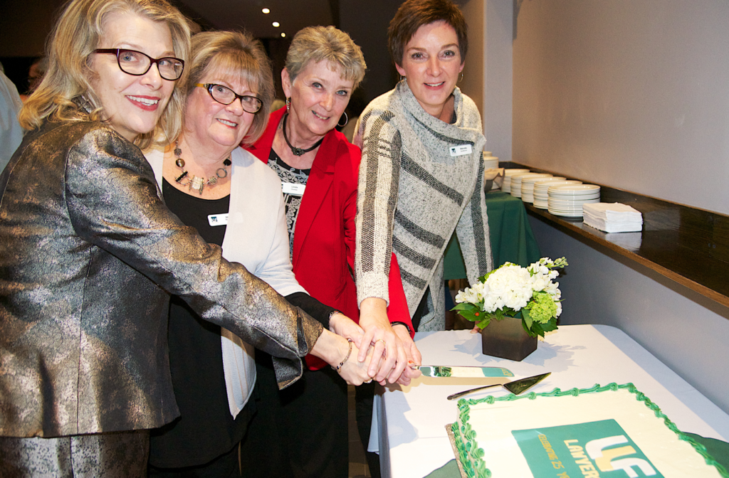 4 original staff members cutting 25th anniversary cake