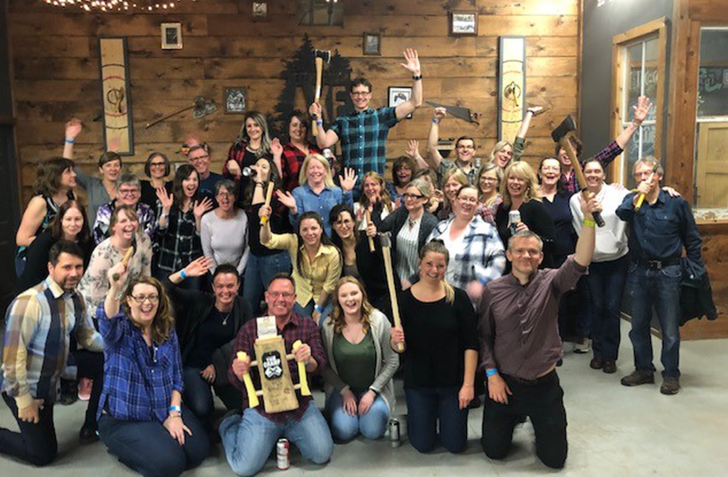 LLF staff cheering with axe-throwing competition trophy