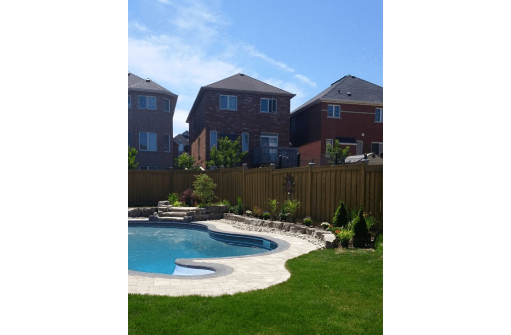 Curved inground pool surrounded by lawn